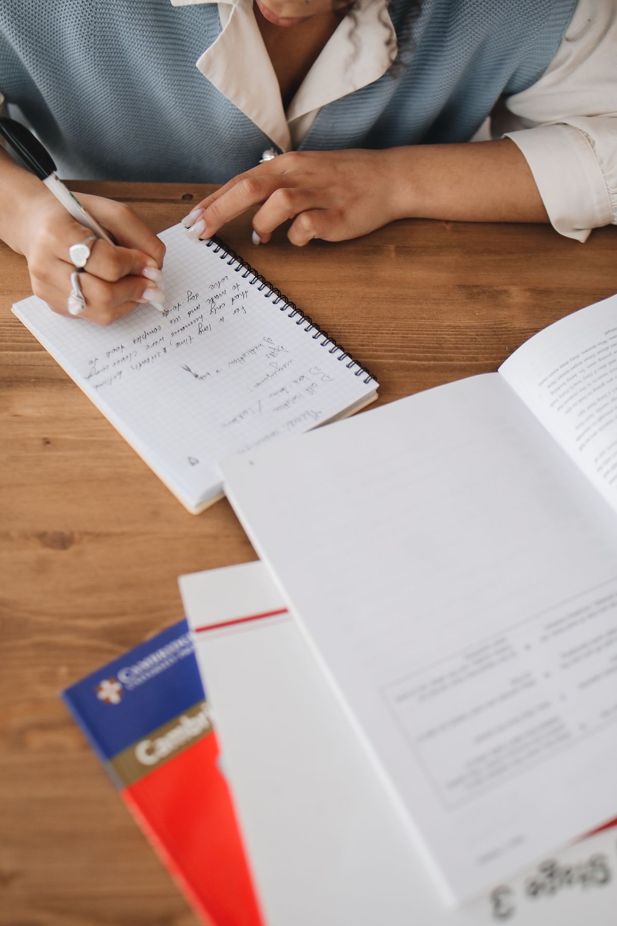 Handwriting practice by a student writing a paper notebook at a wooden desk