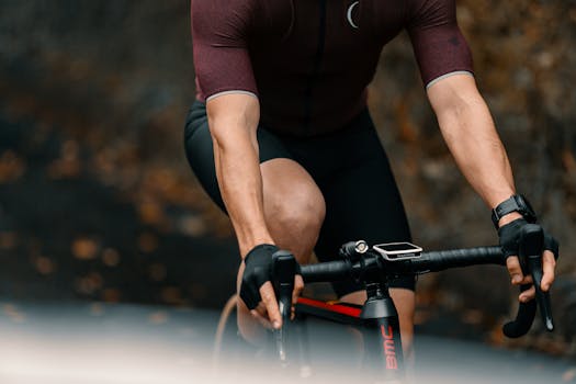 Detailed shot of a cyclist wearing sportswear and gloves riding a road bike outdoors.