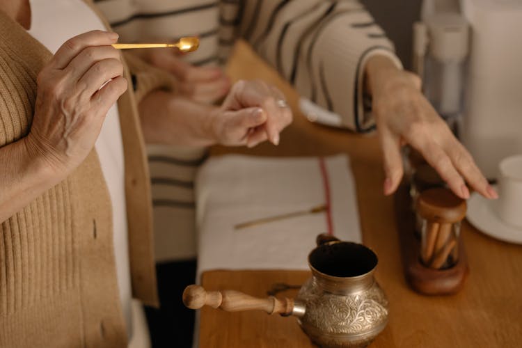 Hand Of A Person Holding A Gold Teaspoon