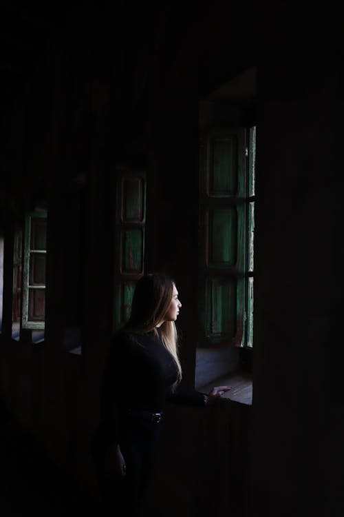 A Woman in Black Long Sleeve Shirt Standing Near Window