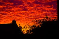 鲜艳的日落天空映衬着米尔顿凯恩斯的屋顶和树叶轮廓