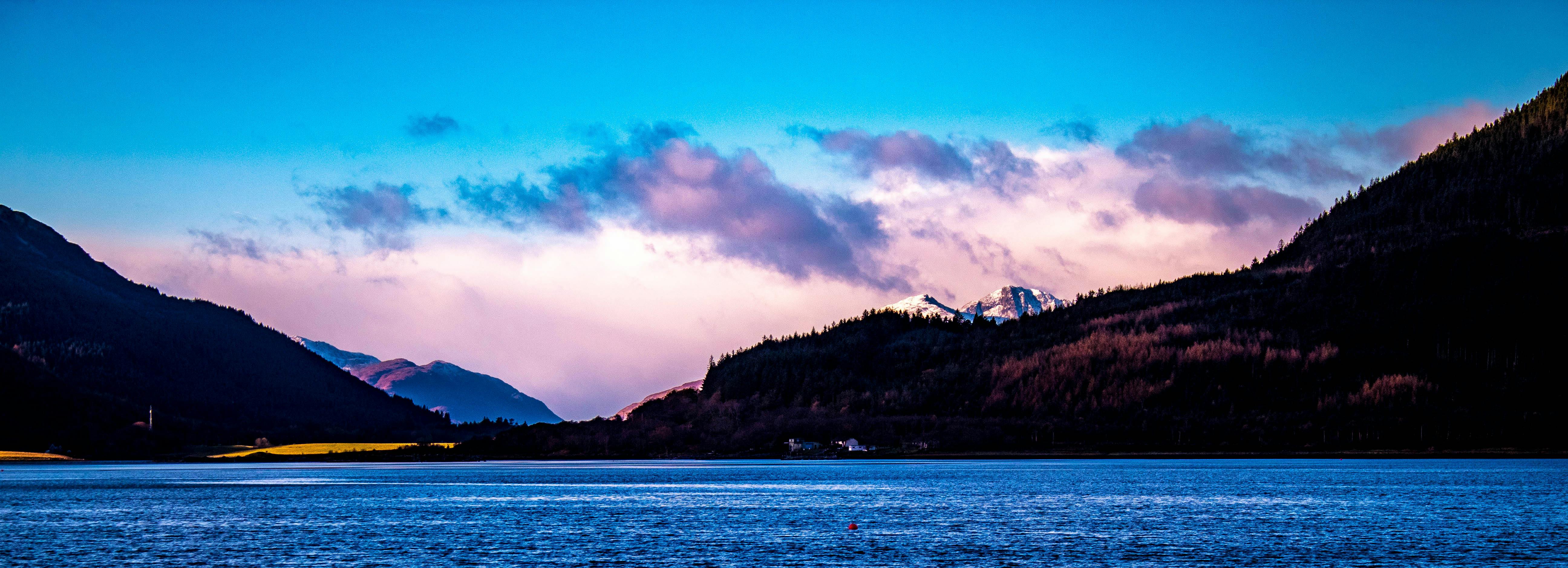 苏格兰高地景色宜人，宁静的海水、雄伟的山脉与黎明时充满活力的天空相映成趣