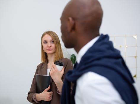 Two young professionals having a casual meeting in a modern office setting, emphasizing teamwork.