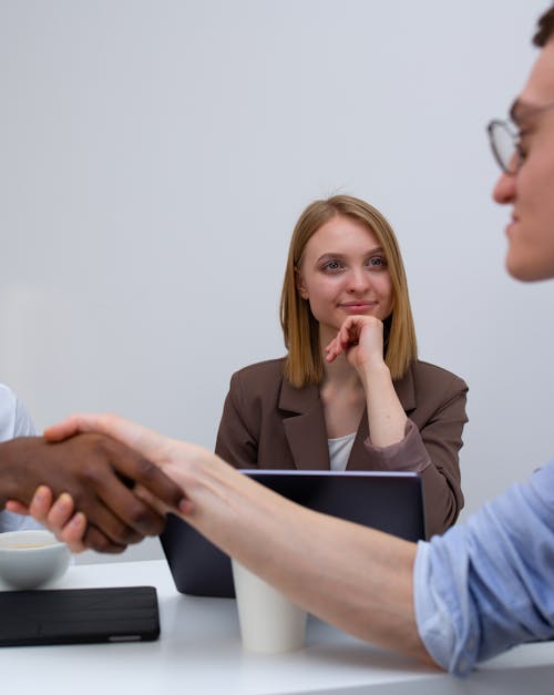 Free A Woman in Brown Blazer Smiling with Her Hand on Her Chin Stock Photo