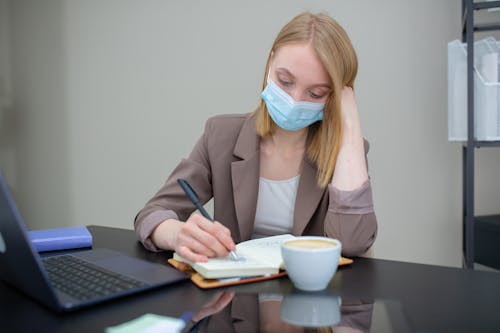 Free A Woman Wearing a Face Mask Taking Down Notes Stock Photo
