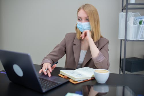 A Woman Wearing a Face Mask Using a Laptop