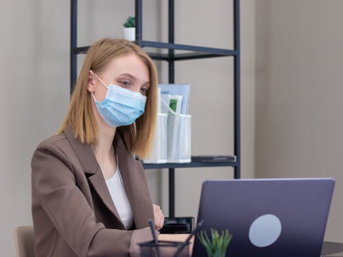 A Woman Wearing a Face Mask Using a Laptop