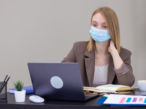 A Woman Wearing a Face Mask Using a Laptop