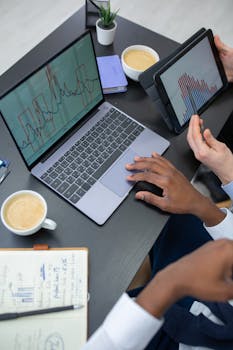 Business professionals analyzing data on a laptop and tablet in a modern office.