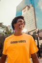 From below of cheerful African American male in bright yellow T shirt smiling and looking away near contemporary glass building
