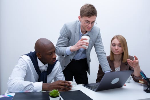 Team of professionals collaborating around a laptop in an office setting.