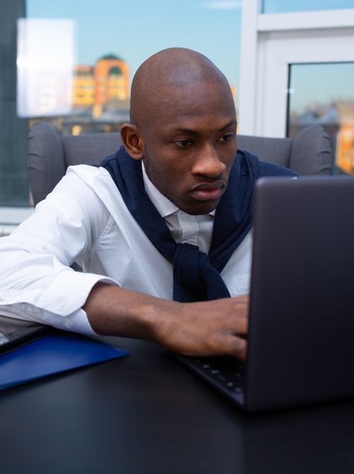 Free Business professional engrossed in work at a modern office desk with a laptop. Stock Photo