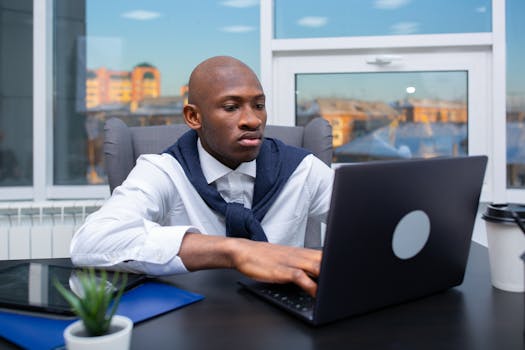 Focused businessman working on a laptop in a modern office setting, conveying professionalism and productivity.