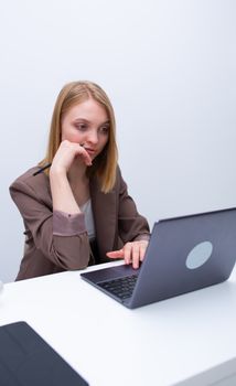 Focused young woman in business attire using laptop in minimalist office setting, enhancing productivity.