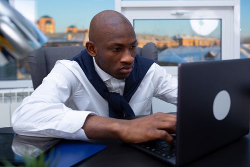 Free Professional man working intently on his laptop in a modern office environment. Stock Photo