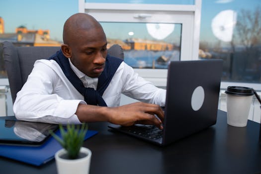 Professional man working intently on a laptop in modern office setting.
