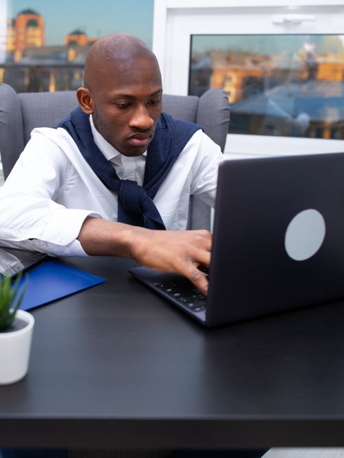 Free Professional businessman concentrating on laptop work in a modern office setting. Stock Photo