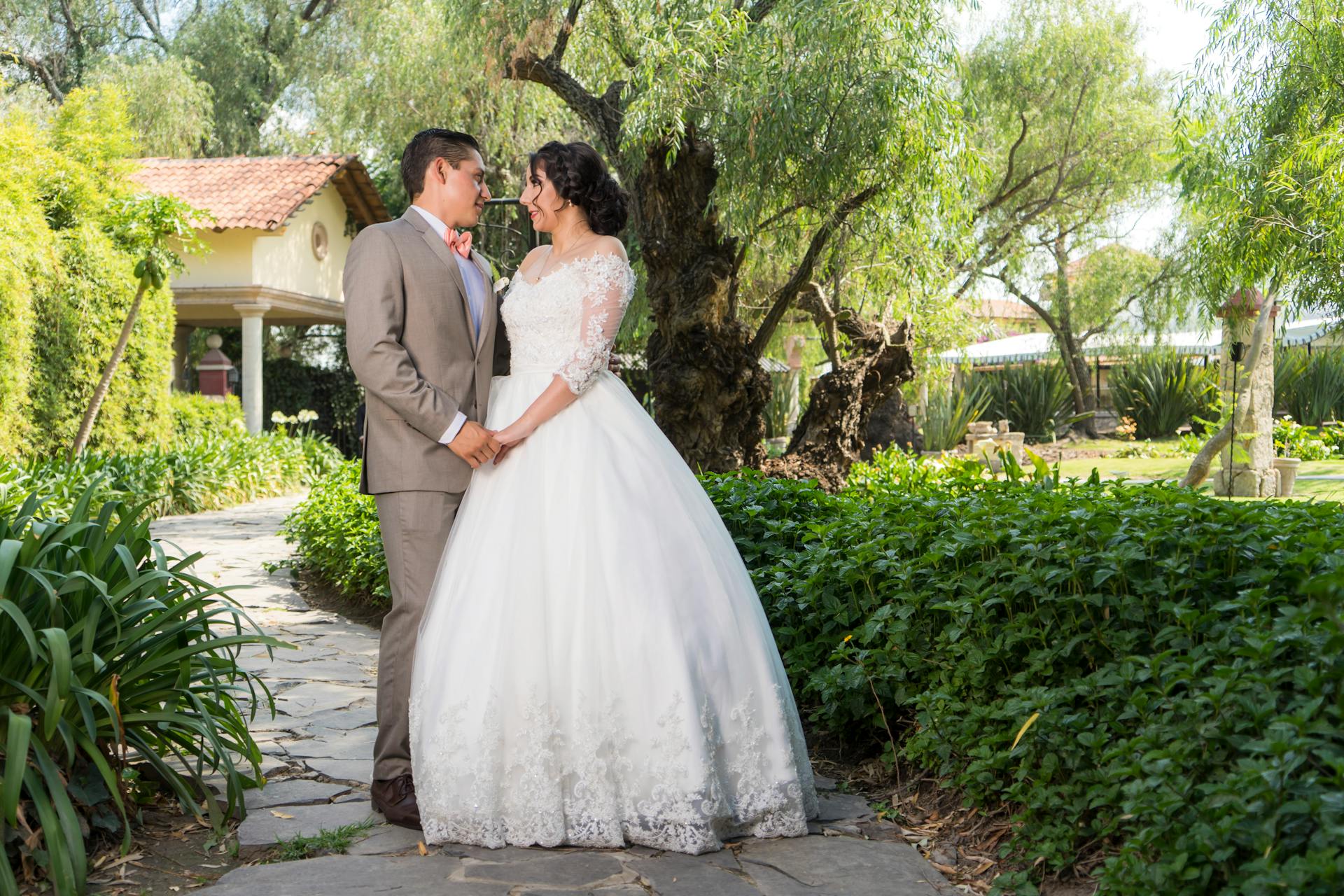 Elegant bride and groom embracing in a picturesque garden, full of love.