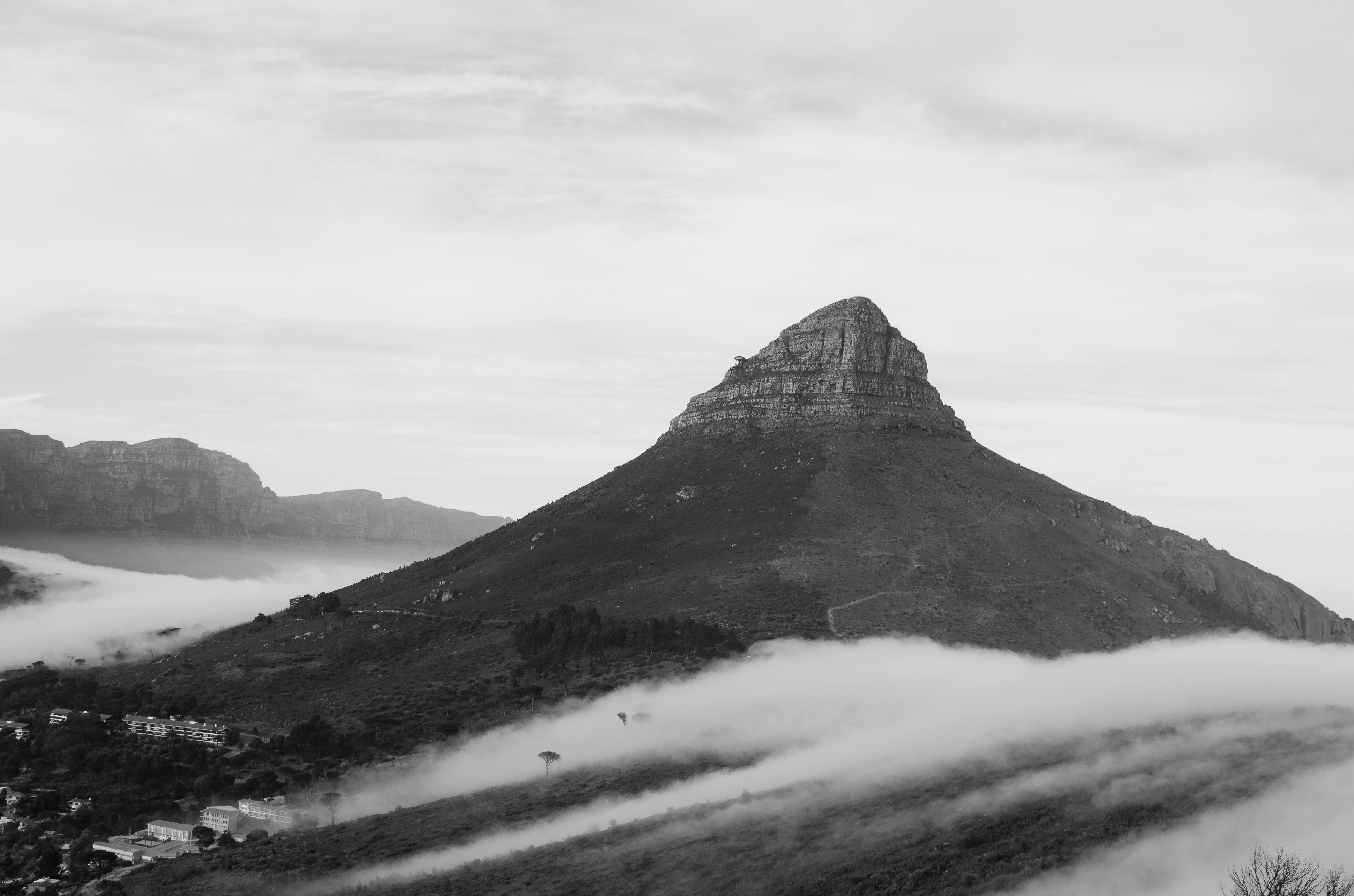 Black and white photo of a misty mountain landscape with fog and clear sky.