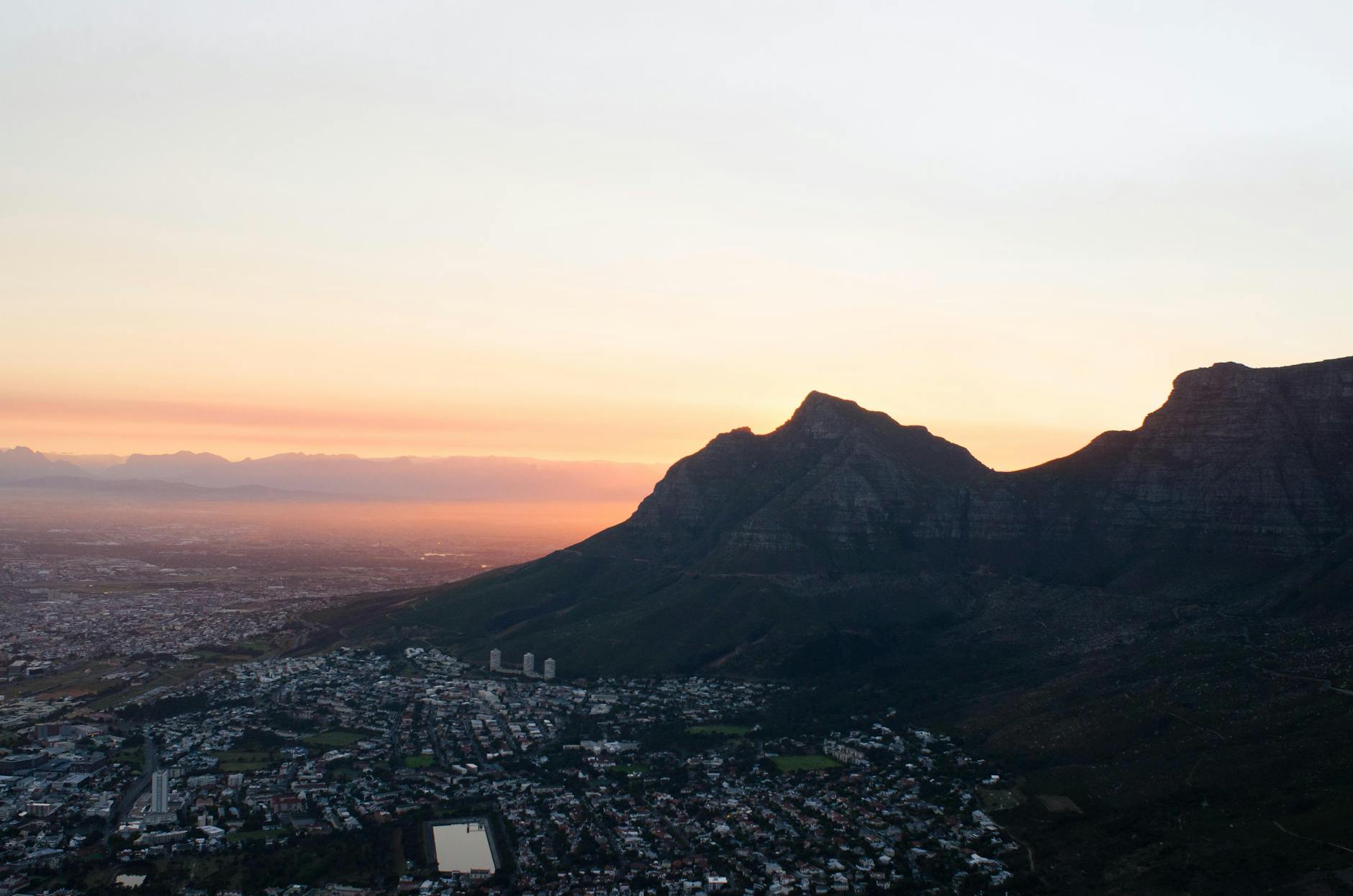 Captivating aerial view of Cape Town at sunset, showcasing Table Mountain's silhouette against a colorful sky.