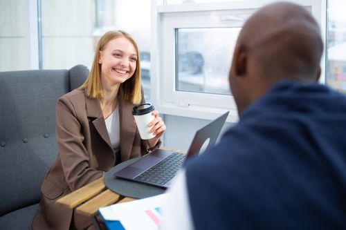 Free Smiling professionals engaged in a coffee meeting at a modern office, enhancing collaboration. Stock Photo