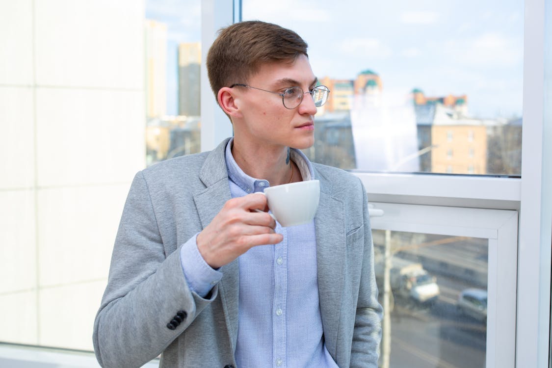 A Man in Gray Coat Drinking Coffee · Free Stock Photo