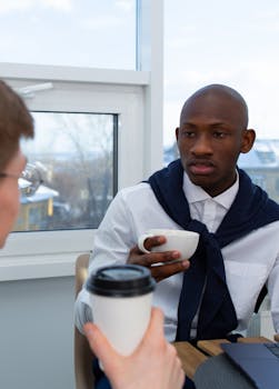 Two businessmen having a meeting with coffee in a modern office setting.
