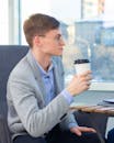 Man in Gray Blazer Holding White Disposable Cup
