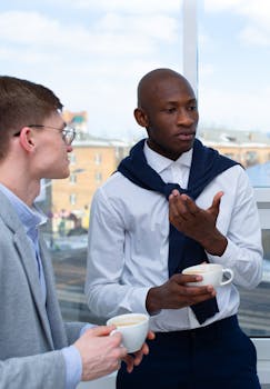 Two businessmen conversing over coffee during a casual office break.
