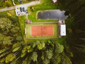 Drone shot of a tennis court surrounded by lush greenery in Estonia.