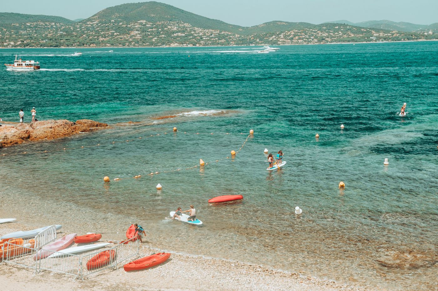 People paddleboarding along a clear coastal shoreline