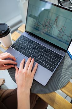 Person typing on a laptop displaying a data chart, symbolizing technology and analysis.