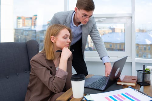 A Man and a Woman Sitting on a Chair in Front of a Laptop 