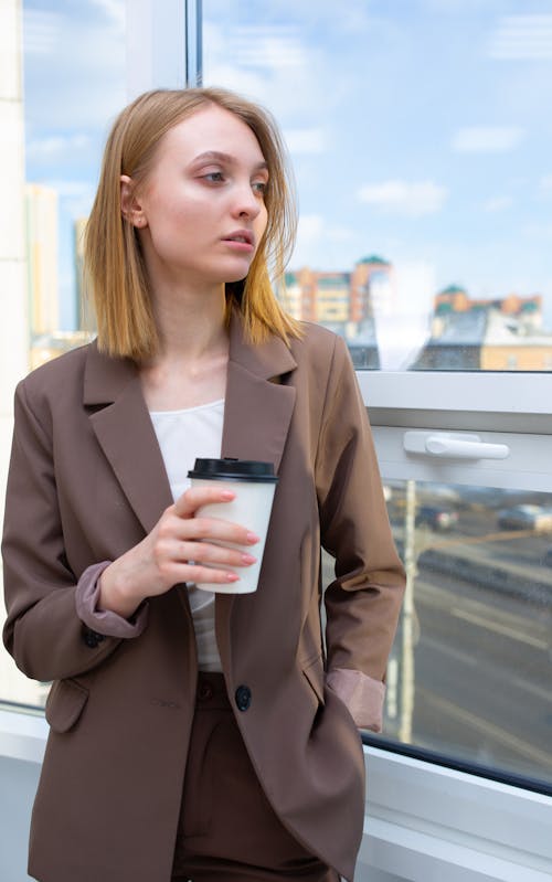 A Woman in Brown Blazer Holding a Cup of Coffee