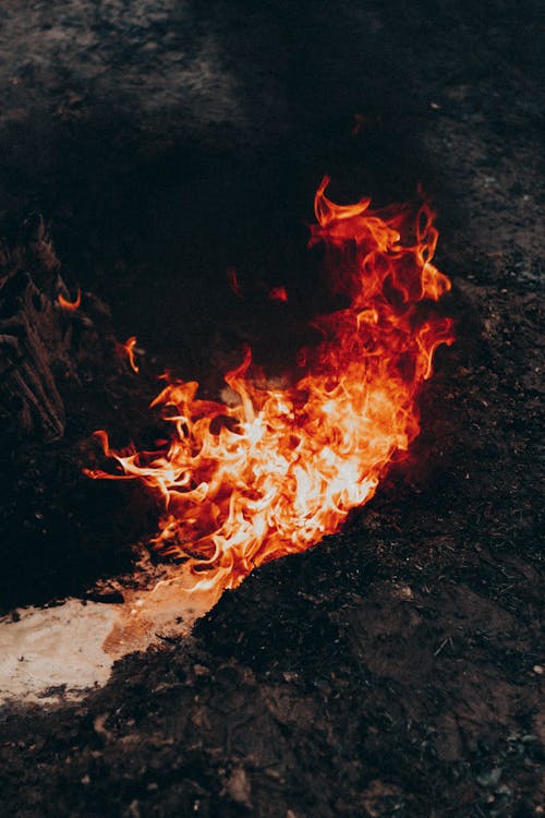 From above of bright blaze forming waves in air above dry terrain at dusk