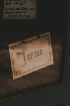 Retro signboard Ferme handing behind glass doors of shop in city street