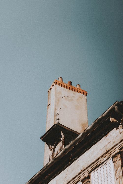 Free Low angle of concrete chimney stack on rooftop of aged building against blue sky Stock Photo