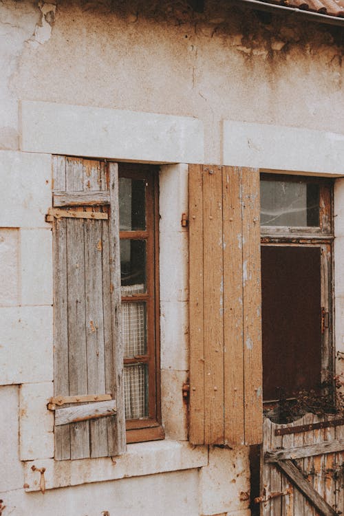 Old wooden shutters on windows of shabby residential house with wrecked walls in countryside