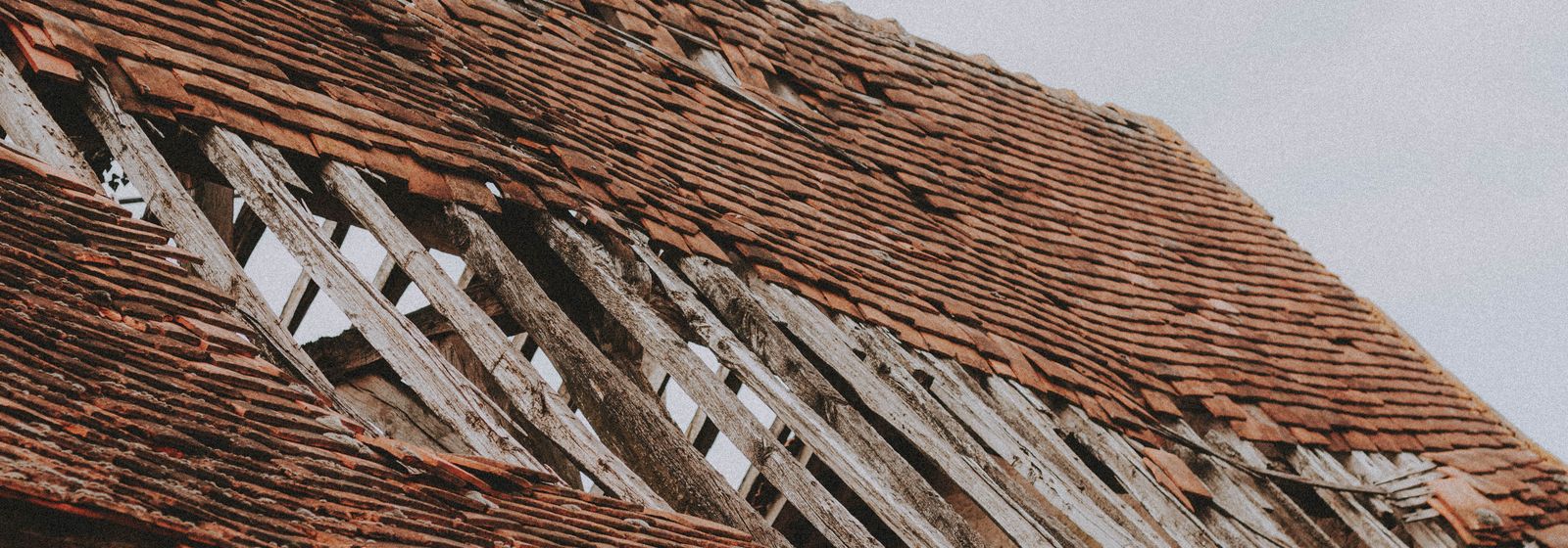 Old roof with missing shingles and exposed boards