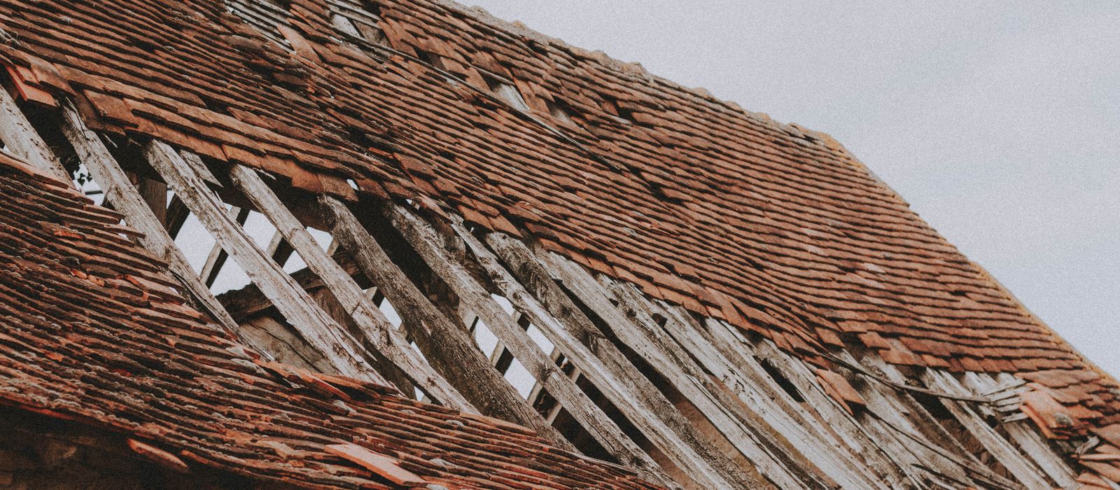 Old roof with missing shingles and exposed boards