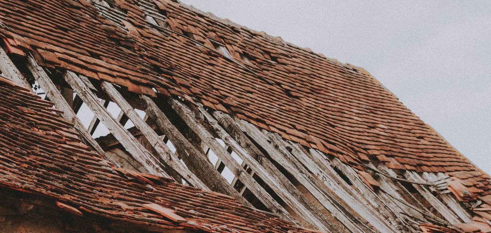 Old roof with missing shingles and exposed boards