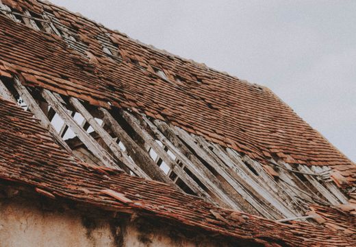 Old roof with missing shingles and exposed boards