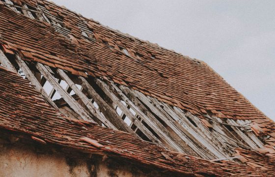 Old roof with missing shingles and exposed boards