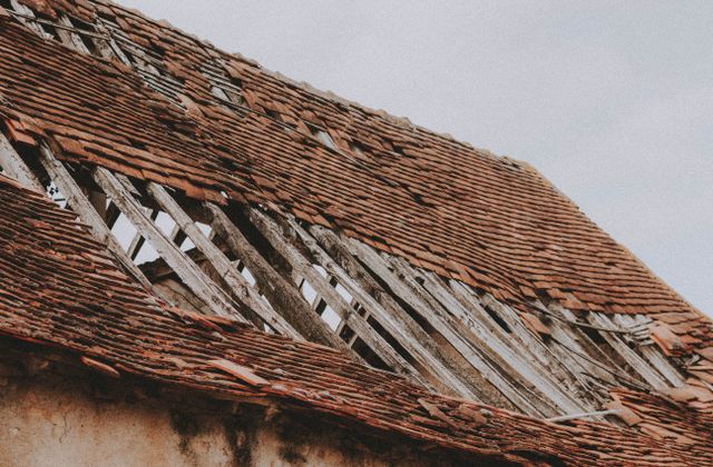 Old roof with missing shingles and exposed boards