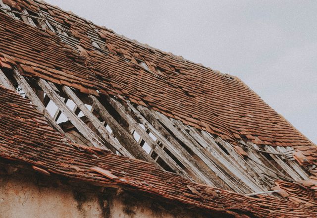 Old roof with missing shingles and exposed boards
