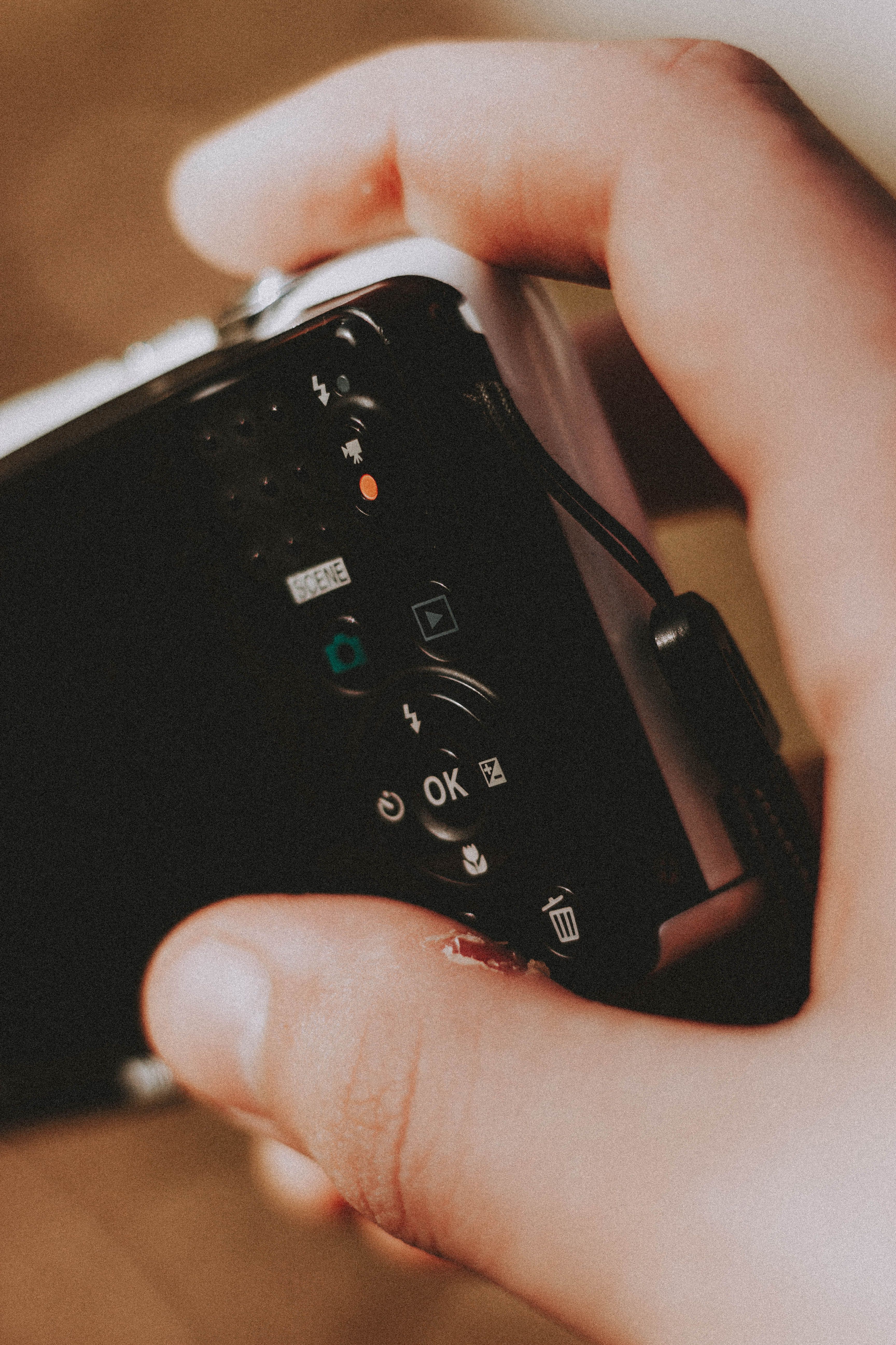 A detailed close-up of a person's hand holding and operating a digital camera.