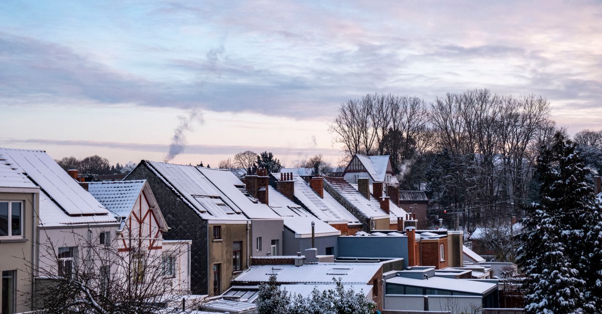 Schneebedeckte Dächer eines Wohngebiets in der Morgendämmerung, die den Heizenergiebedarf im Winter verdeutlichen.