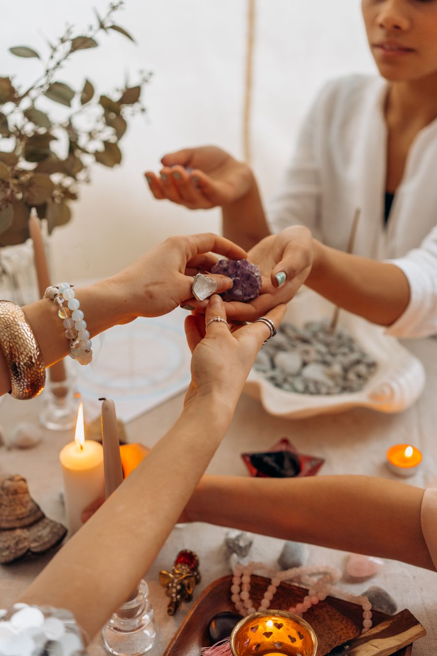 Two pairs of hands holding amethyst crystals by candlelight