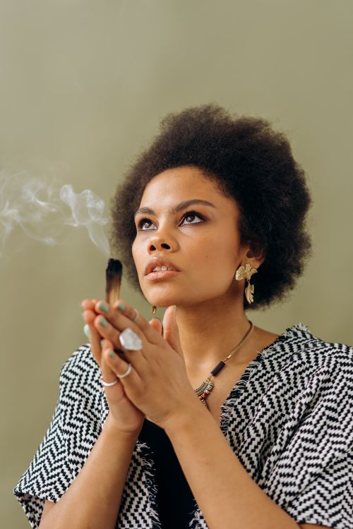 Free Young woman with afro hair holding burning palo santo for a relaxation ritual. Stock Photo