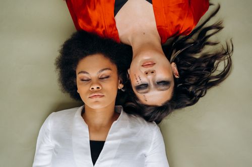 Free Two women in meditation pose lying head-to-head, embodying peace and spirituality. Stock Photo